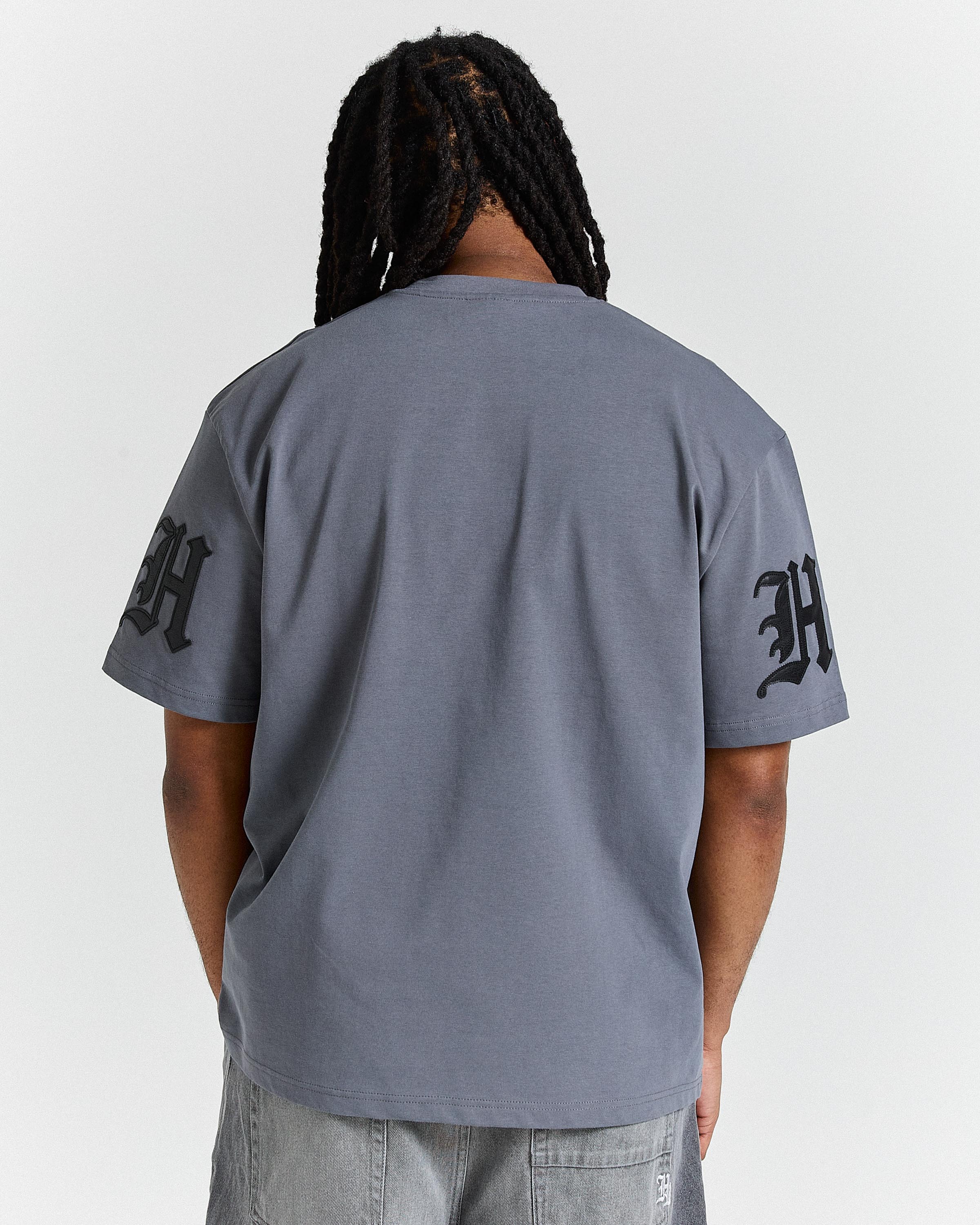 Person wearing a gray t-shirt with black text on sleeves against a white background