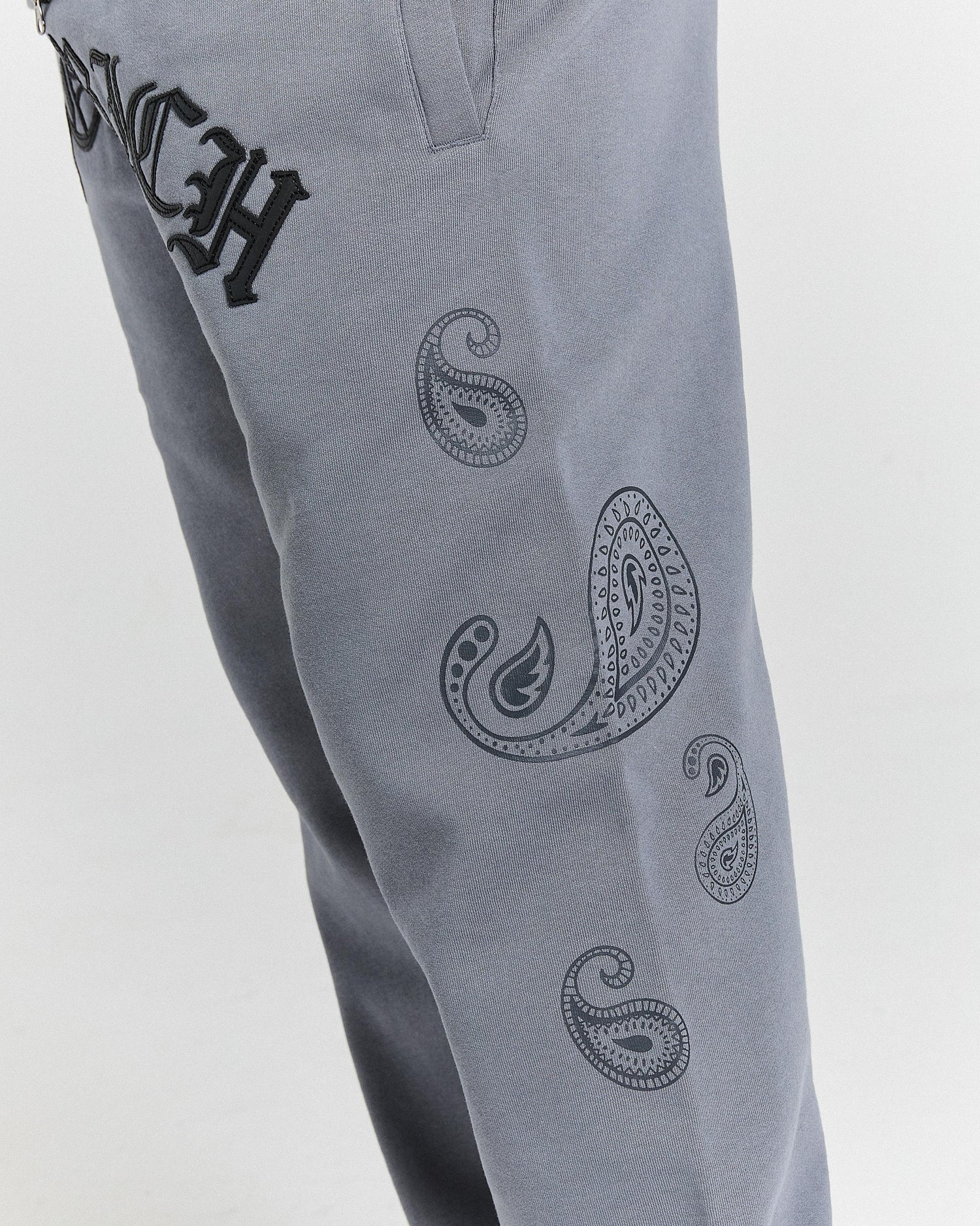 Gray pants with black paisley patterns and text on a light gray background