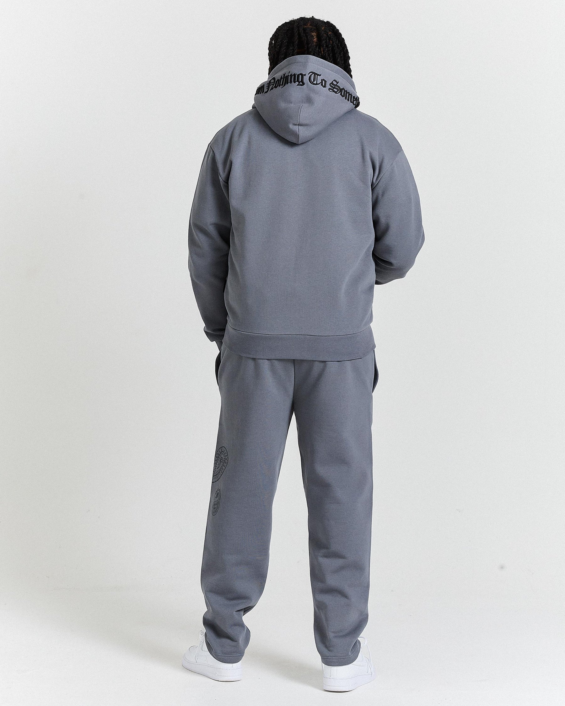 Person wearing a gray tracksuit with a hood on a white background
