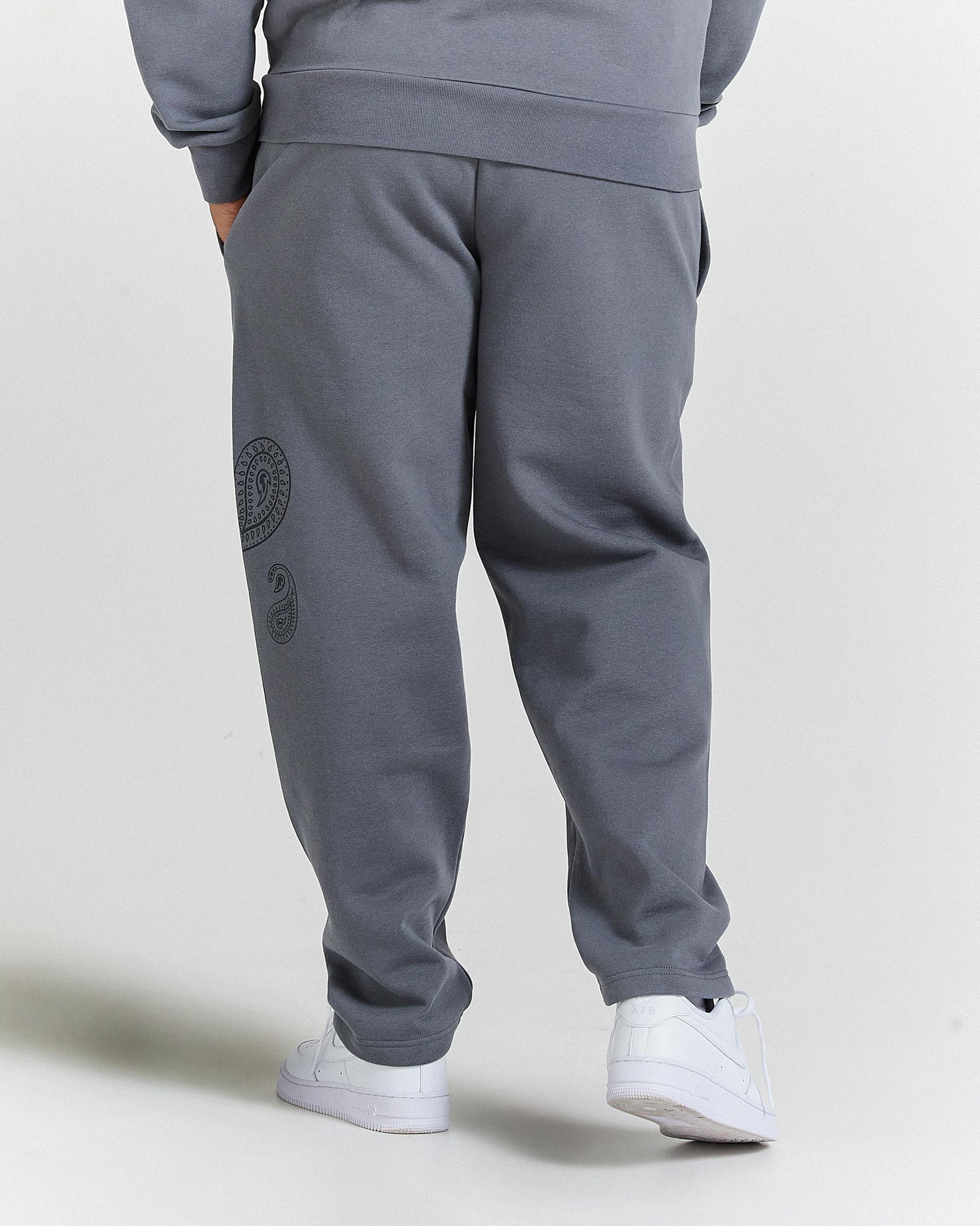 Gray sweatpants with a logo on the back pocket against a light gray background