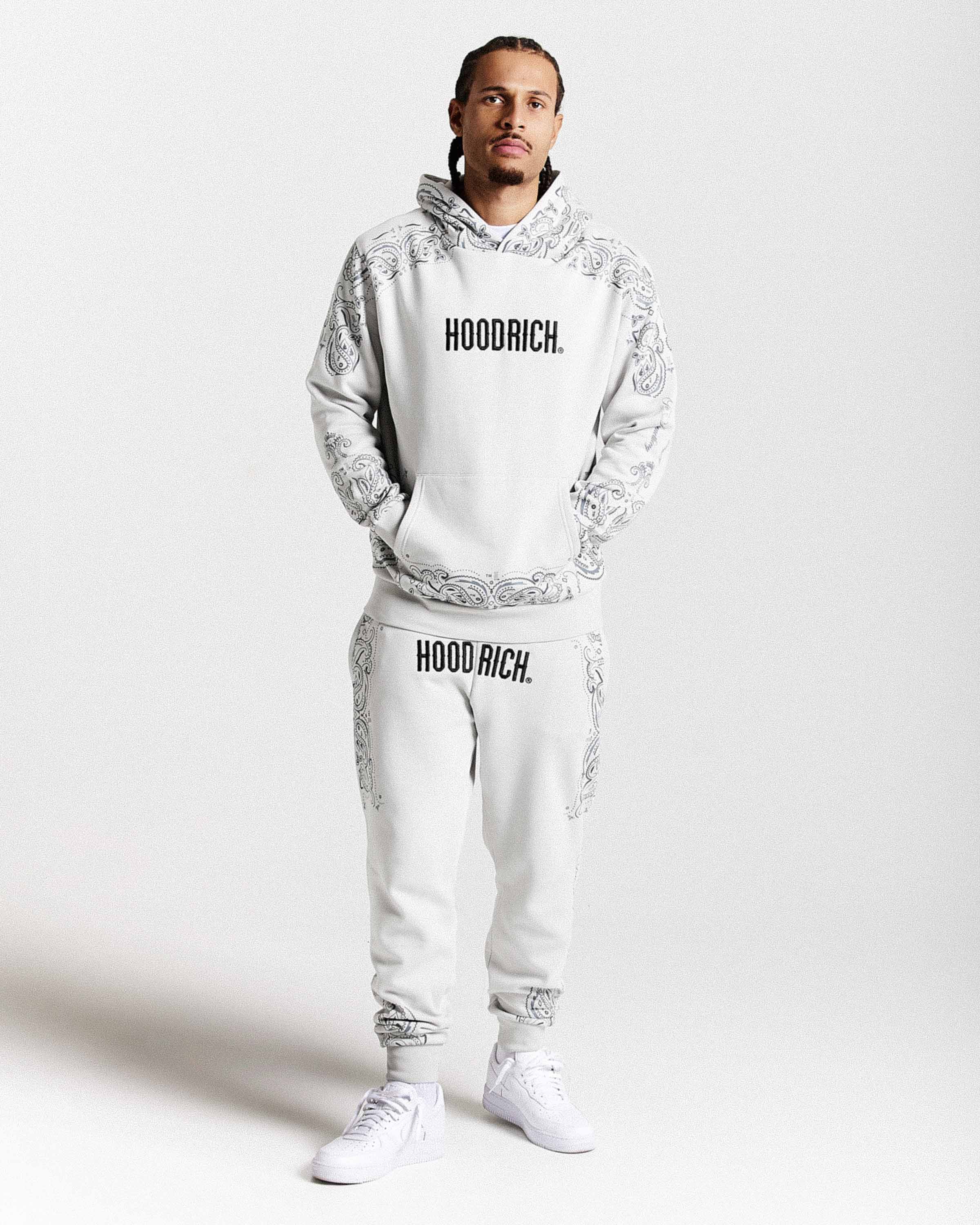 Person wearing a white 'Hoodrich' tracksuit on a light gray background