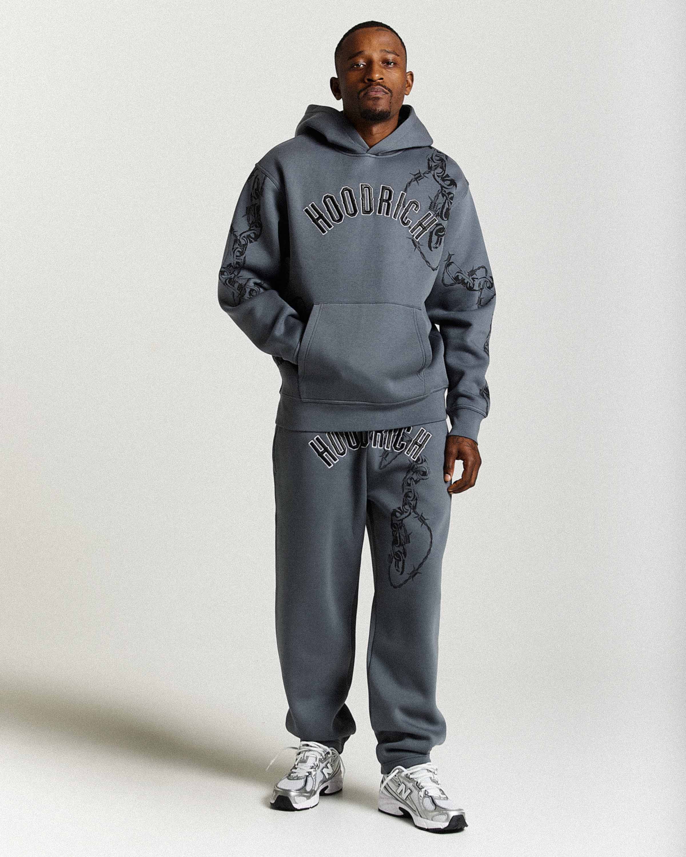Person wearing a gray 'Hoodrich' hoodie and pants on a white background