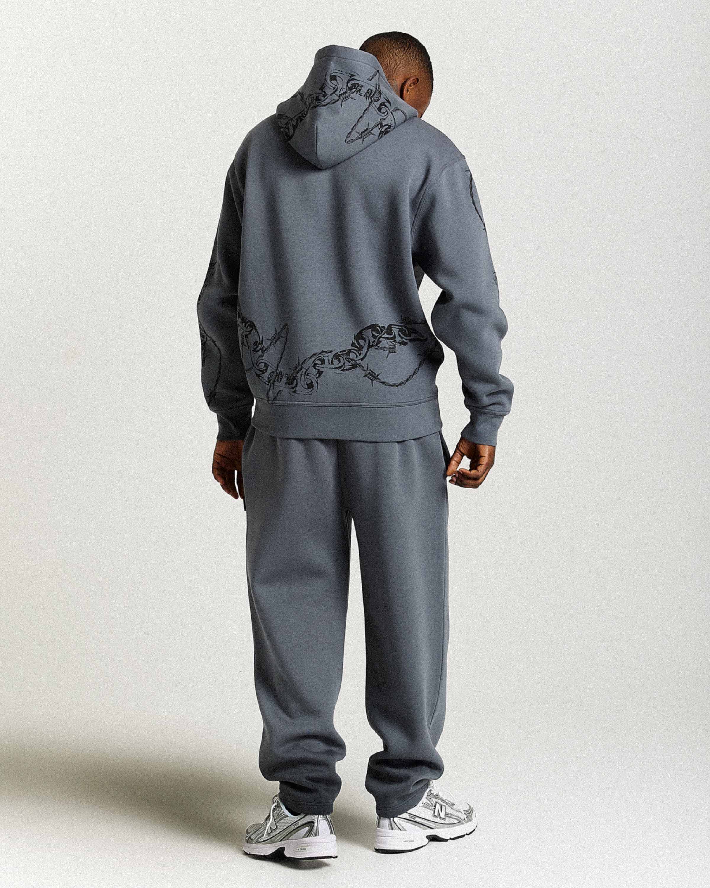 Person wearing a gray tracksuit with a hood on a white background